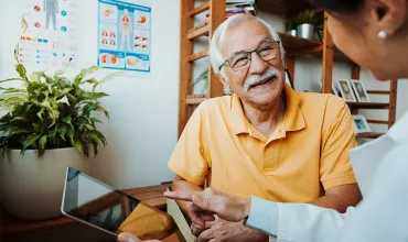 A healthcare professional and senior patient in a conversation using a tablet