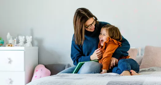 Mother and daughter cuddling on a bed in a kids room