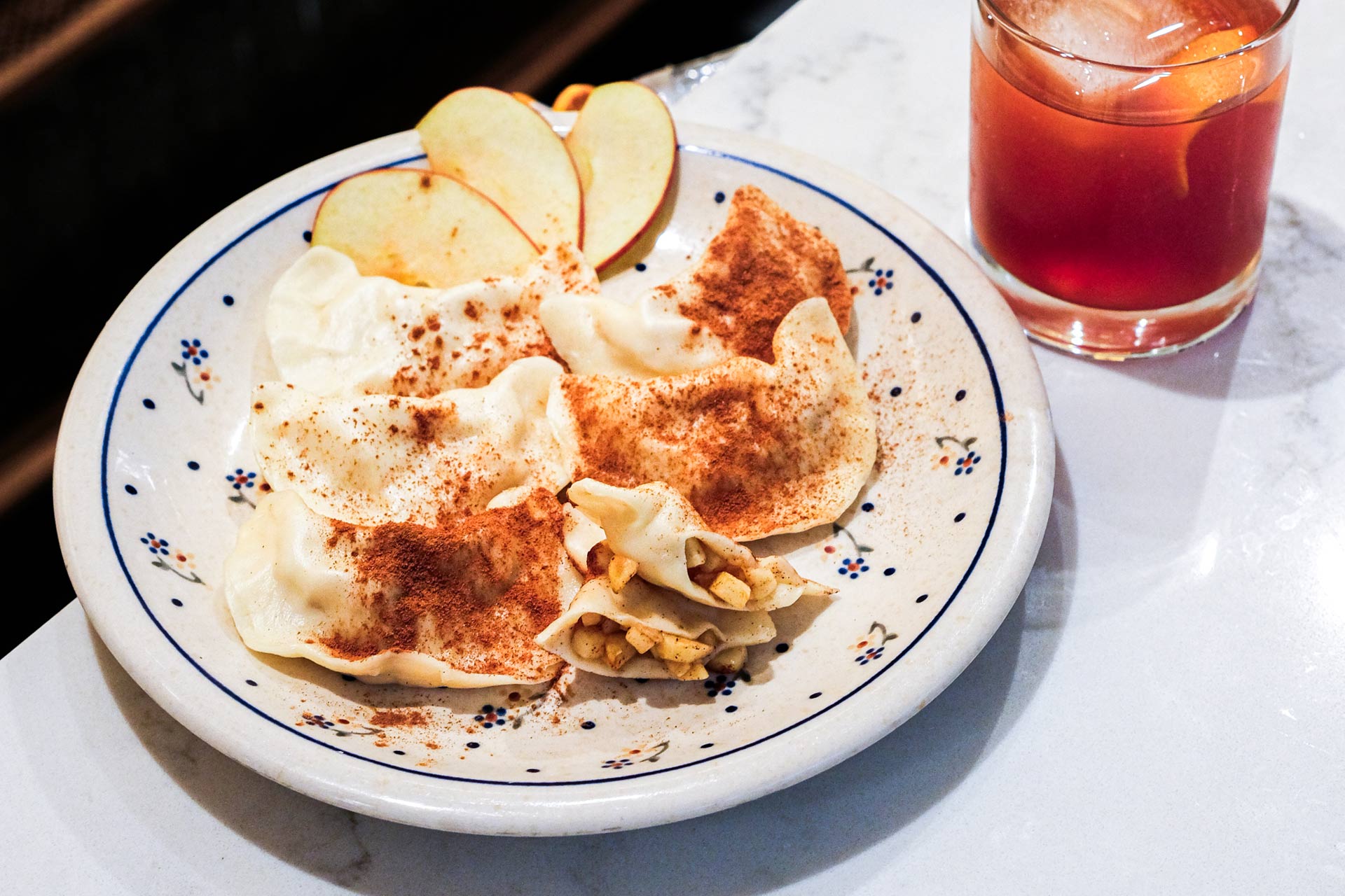 A plate of Polish pierogis and a a negroni cocktail