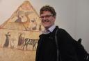 Dr Paul Roberts OBE in front of a painted tomb panel from Paestum in the exhibition Last Supper in Pompeii