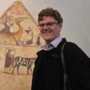 Dr Paul Roberts OBE in front of a painted tomb panel from Paestum in the exhibition Last Supper in Pompeii