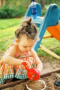 Toddler digs sand at a playground.