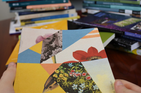 Hands holding a journal with more journals stacked in the background.