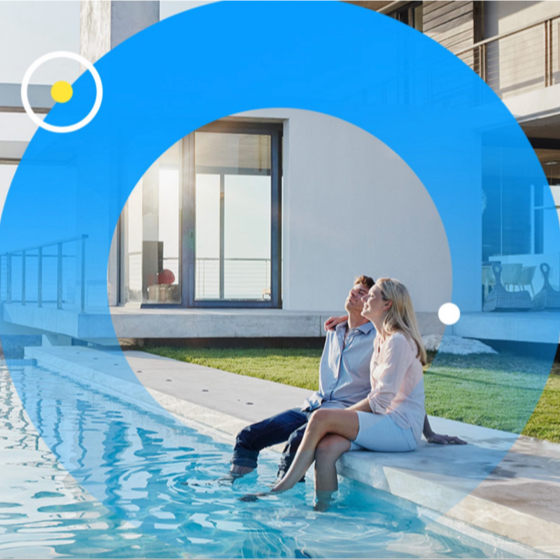 smiling couple sitting by a backyard pool