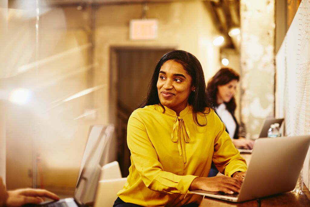 A photo of a woman using her laptop checking the timesheet portal