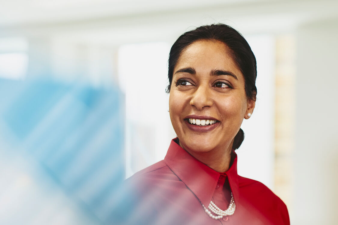 an image of a woman wearing a red collared blouse smiling while looking to the left