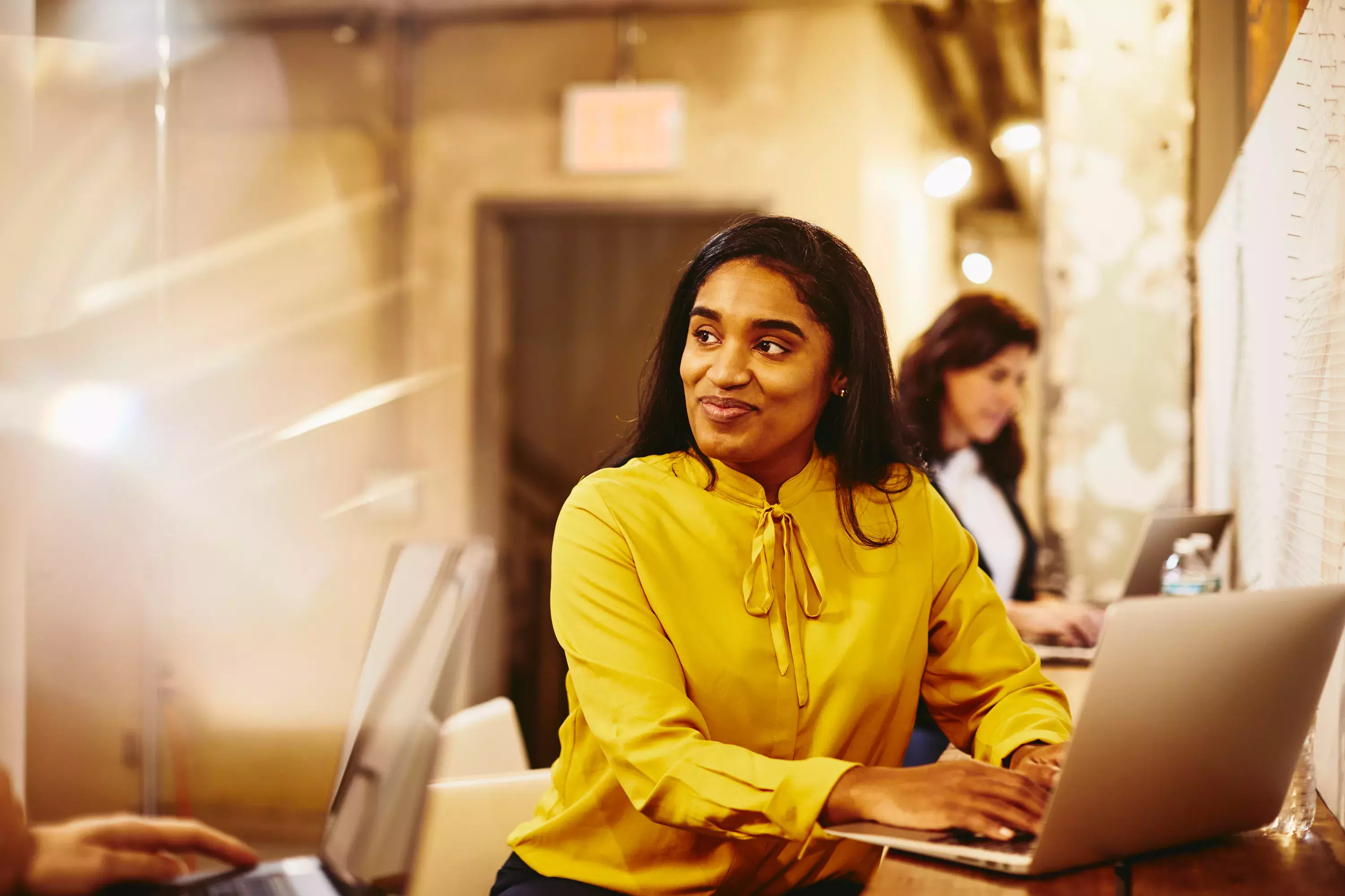 Two smiling female working on their laptop.
