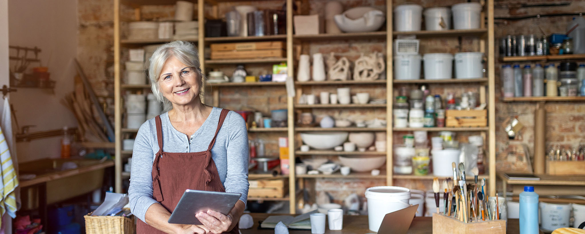 Older woman looking at her tablet in a pottery studio