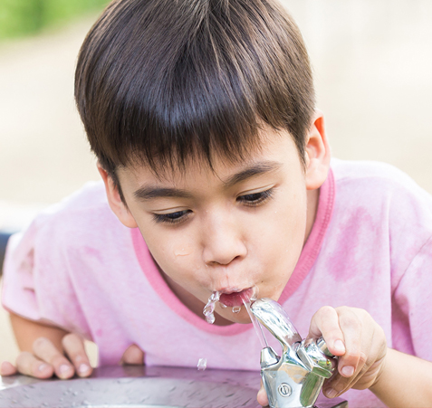 A boy drinking from a water fountain