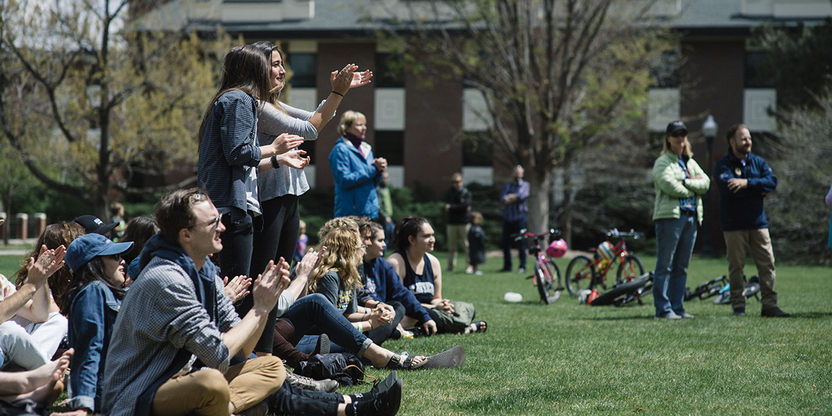 students sitting and clapping on the quad