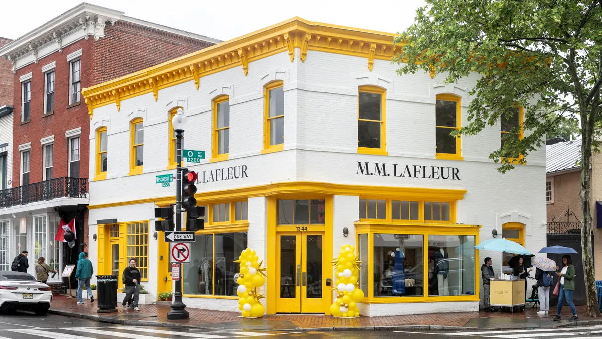 A white store with yellow trim, with the words "M.M. LaFleur" painted in black.