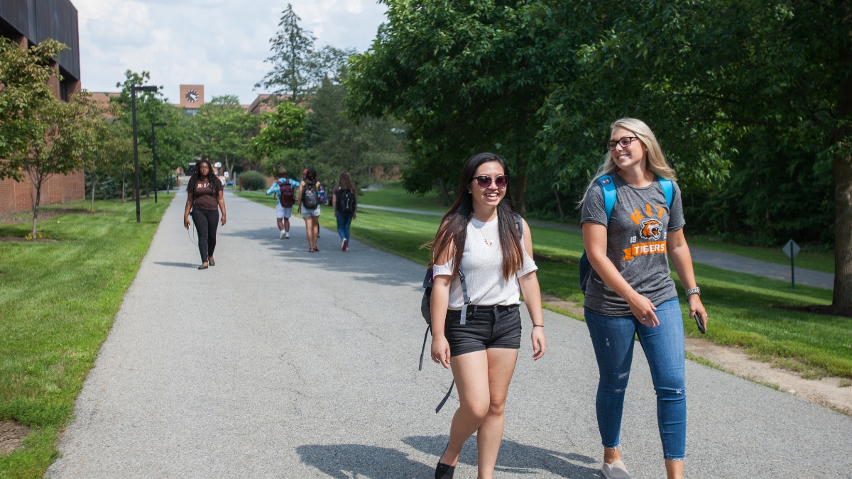 Two students smiling, while walking on campus.