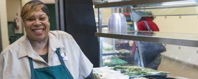 A food service employee serves lunch