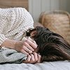 girl lying on side with blanket pulled up to face