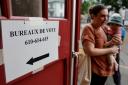 A woman holds her child outside a voting station in Strasbourg, eastern France (Jean-Francois Badias/AP)