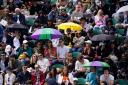 Spectators sheltered from the rain as awaited the start of play on day seven of Wimbledon (Jordan Pettitt/PA)