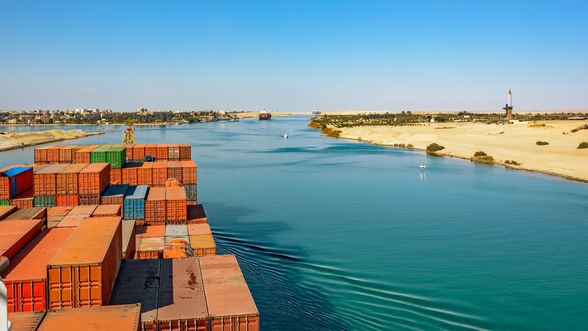 Industrial container ship passing through Suez Canal with ship's convoy, view on the bow from the captain bridge.