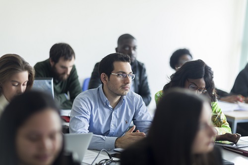 Man sitting in classroom wearing a blue shirt