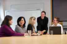 Five people gather around a table in discussion