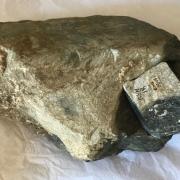 The bluestone boulder showing eroded and weathered surfaces and one of the samples taken by geologists