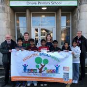 Cllr Jim Grant, Craig Roberts and Bryony Bardwell from Drove Primary School, and Detective Superintendent Guy Elkins with pupils and the Broadgreen community logo