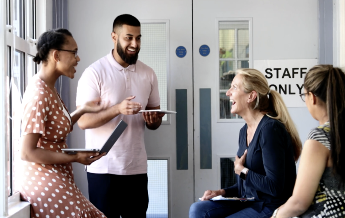 Photo of four teachers laughing together in the teacher's lounge