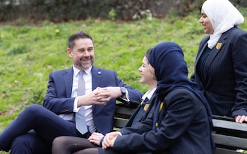 A teacher and pupils sitting on a bench outside a Mayfair school 