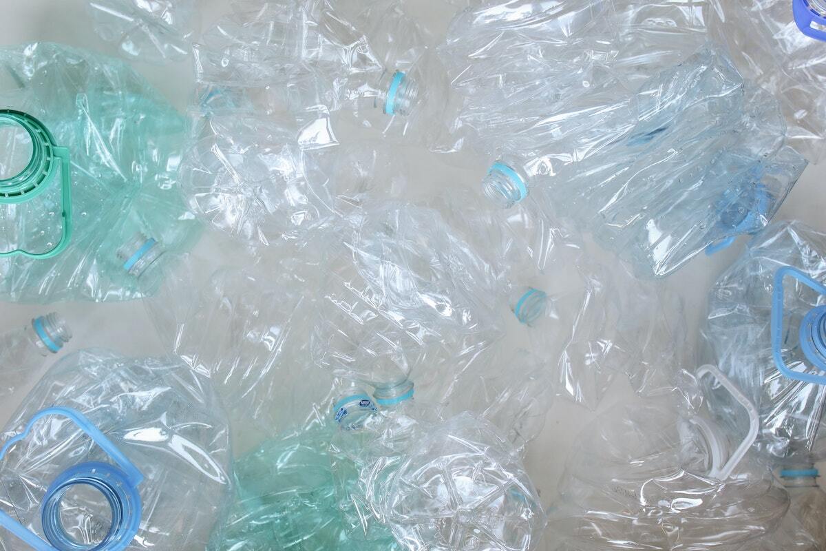 a variety of green and clear water bottles crushed without lids - the wrong way to recycle!