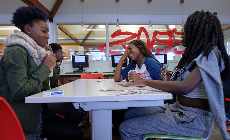 A group of teens sitting at a table, smiling