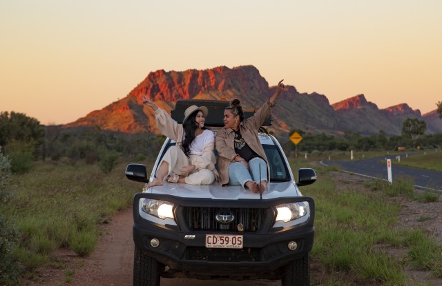 Friends sitting on 4WD bonnet on the side of the road