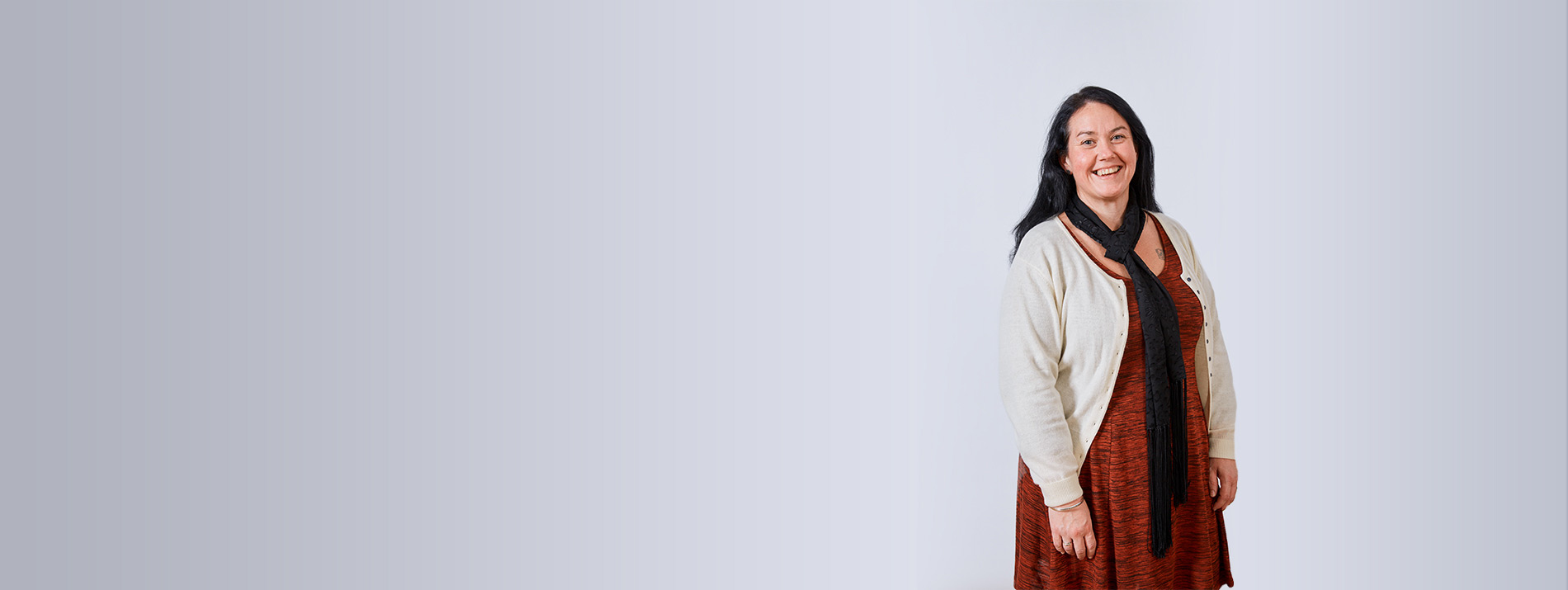 Portrait of a happy looking woman in a red dress with a white cardigan on top.