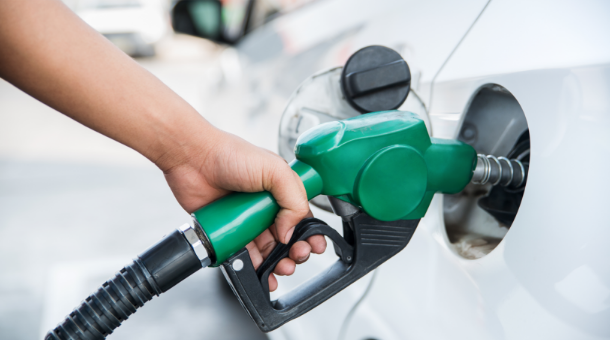 A person's hand gripping a fuel nozzle, refueling a vehicle's gas tank