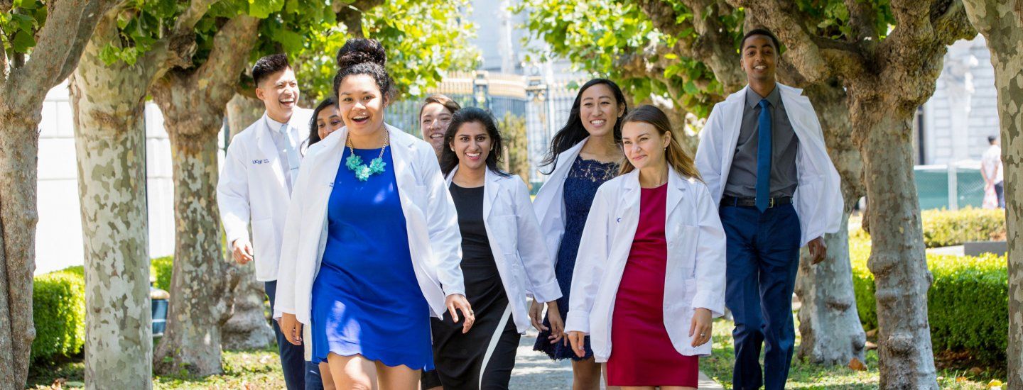 students wearing white coats walking down a walkway