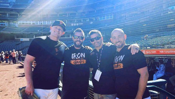 Surgeon Scott Hansen stands in a baseball field with Logan Webb and two men, who are part of the San Franscisco Giants' training staff.