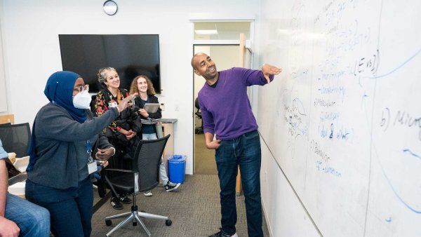 Corey Harwell shows calcualtions on a whiteboard to his lab's staff