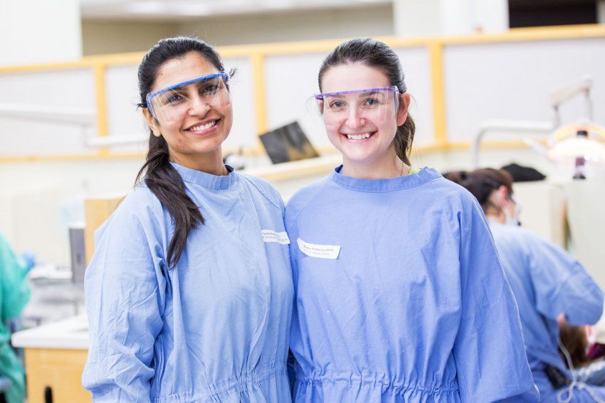 2 dentistry students smiling in a clinic