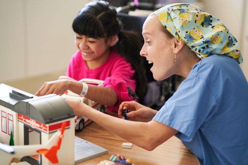 A clinical laboratory scientist plays with a young patient in a schoolroom at Benioff Children's Hospital Oakland.