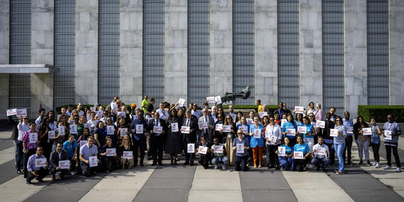 In support of humanitarian efforts, UN personnel and partners display signs to raise awareness about the critical need to protect those on the frontlines of crisis and conflict