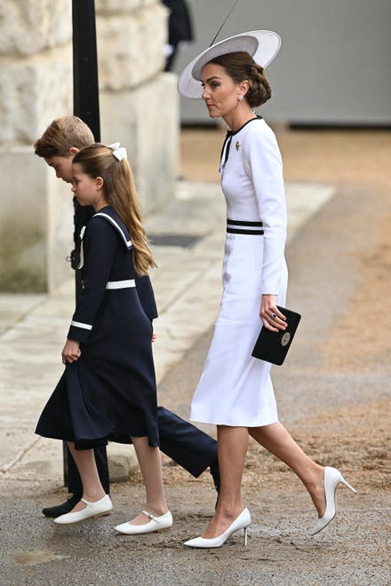 Kate, wearing a pale outfit, arrives with her children Princess Charlotte and Prince George before the "Trooping the Colour", an annual military parade near Buckingham Palace that marks the official birthday of the British monarch, King Charles, in London on June 15, 2024.