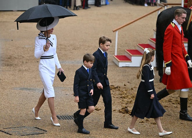 Britain's Catherine, Princess of Wales, shelters from the rain with an umbrella as she walks with her children Britain's Prince George of Wales (C), Britain's Princess Charlotte of Wales (R) and Britain's Prince Louis of Wales back to the Glass State Coach at Horse Guards Parade during the King's Birthday Parade "Trooping the Colour" in London on June 15, 2024. Catherine, Princess of Wales, is making a tentative return to public life for the first time since being diagnosed with cancer, attending the Trooping the Colour military parade in central London.