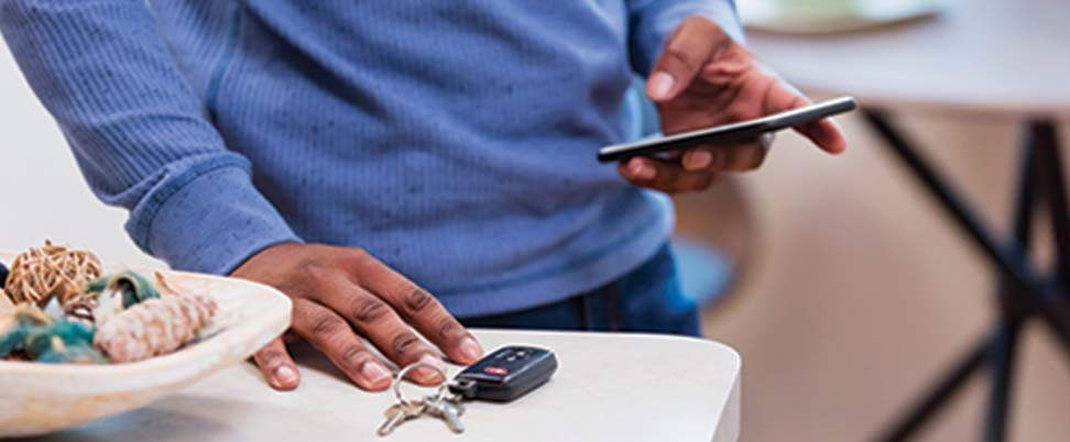 Man reaching for keys while checking his phone