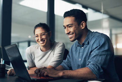 Two young workers using a laptop in a modern office