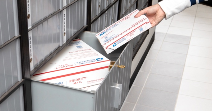 Person retrieving Priority Mail packages from an Extra Large PO Box.