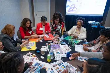 A group of attendees sitting at table creating financial vision boards