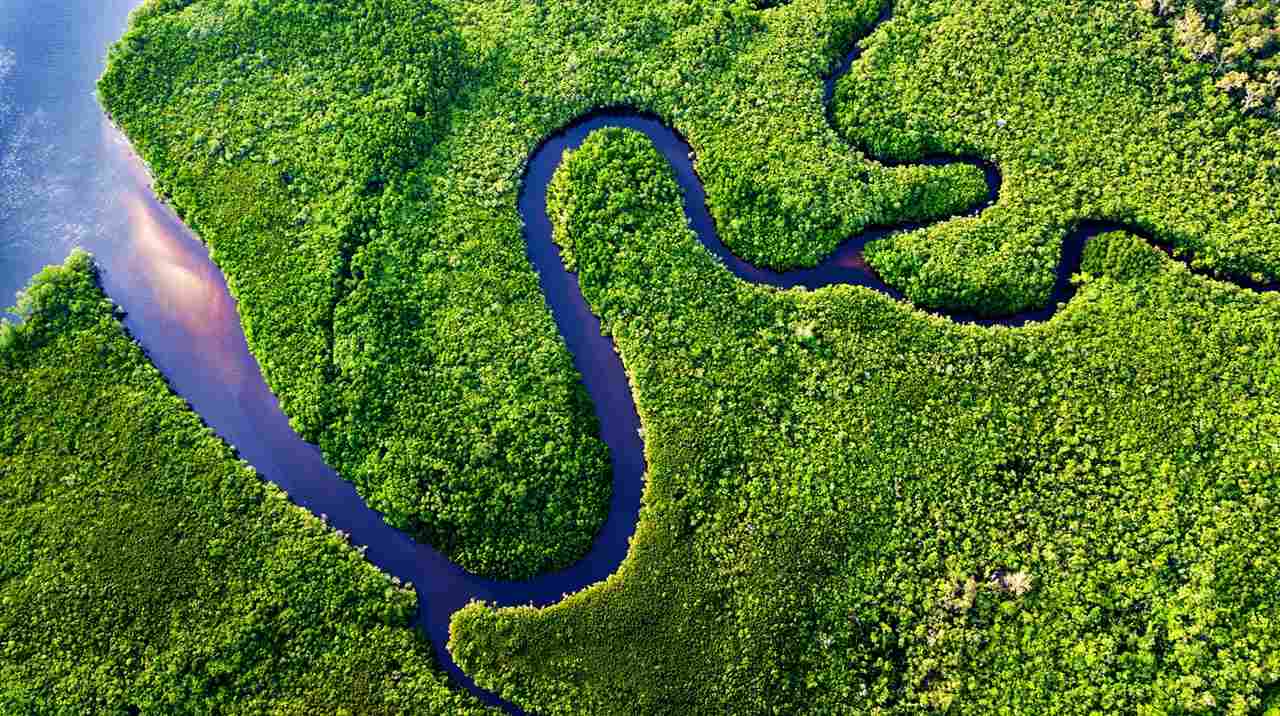 Lush green mountains with a winding river flowing through, symbolising sustainability and the harmony of nature.