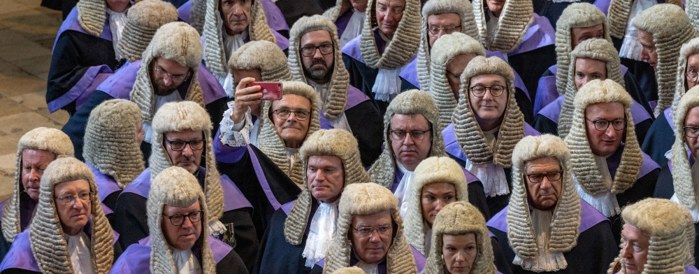 A group of judges, one is taking a selfie on his smartphone