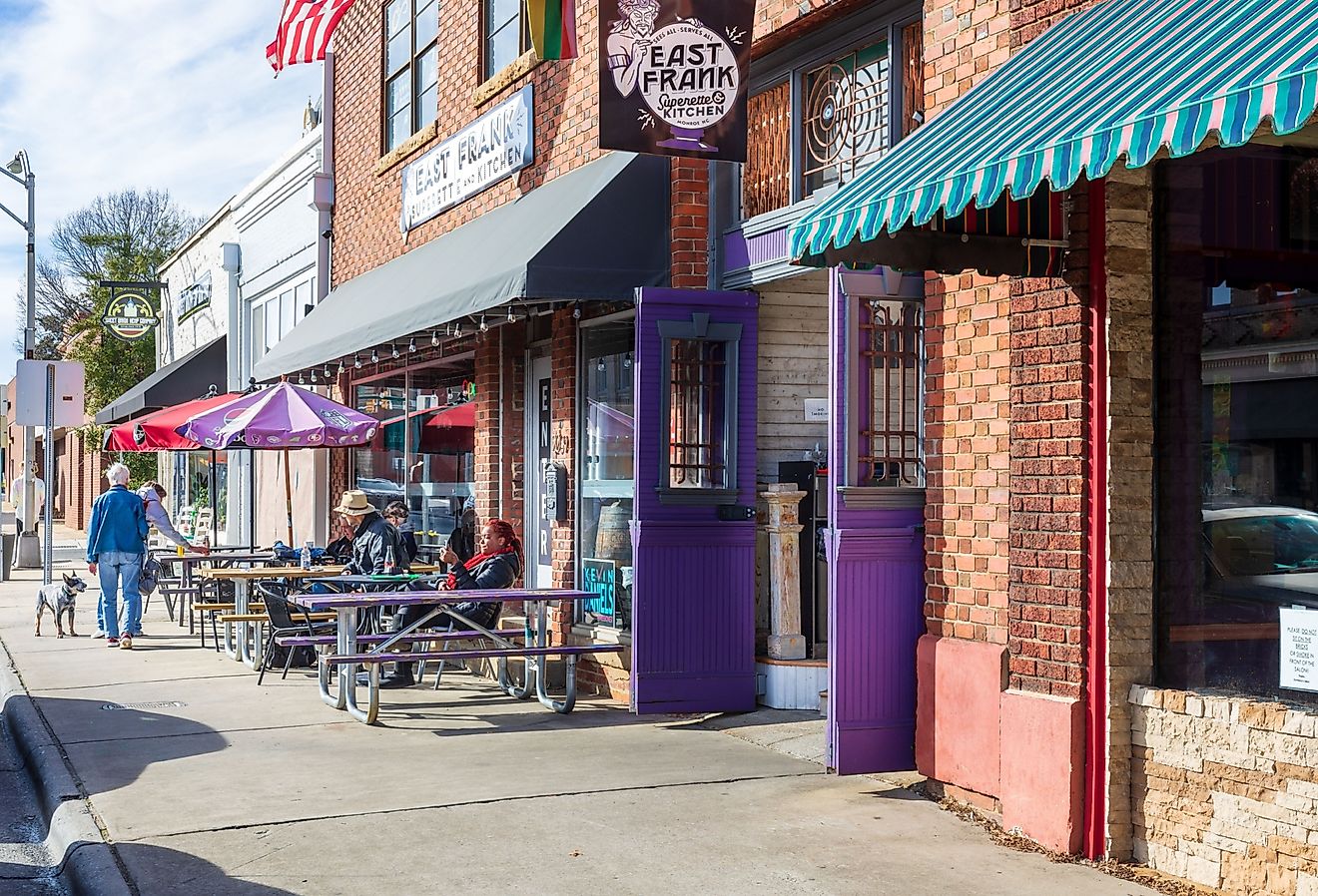 Sidewalk scene with people sitting at tables in front of East Frank's Superette Kitchen in Monroe, NC. Image credit Nolichuckyjake via Shutterstock.