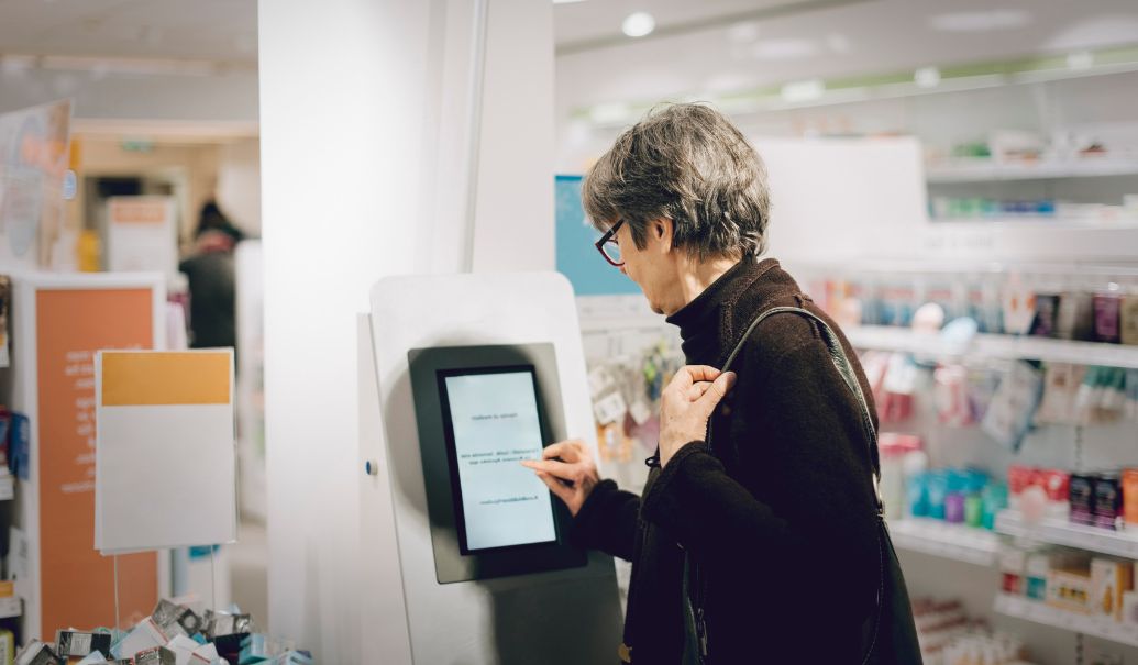 Elderly-woman-looking-into-the-kiosk-in-a-pharmacy-store-insight