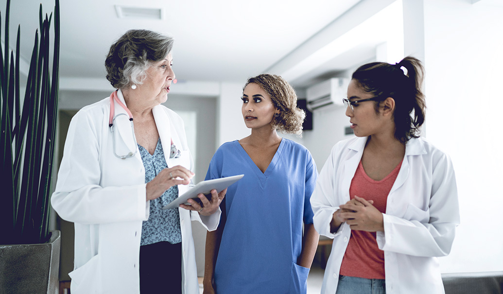 Female-doctors-and-nurse-walking-and-talking-using-digital-tablet-at-hospital-insight