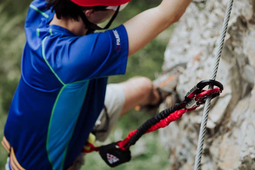 Close up showing the dual carabiners and shock absorber of a via ferrata set in action